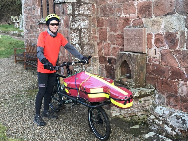 Pilgrim Cello 1 800x600-min Kenneth with his custom bike with the cello on the front standing beside a red sandstone church